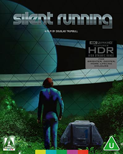 A person stands in a forest looking at a space station against a planet.