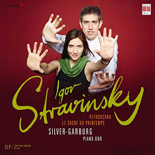 Silver-Garburg Piano Duo posing with hands raised against a dark red background.