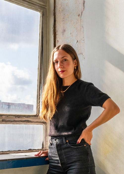 Young woman with long hair standing by a window with peeling paint.