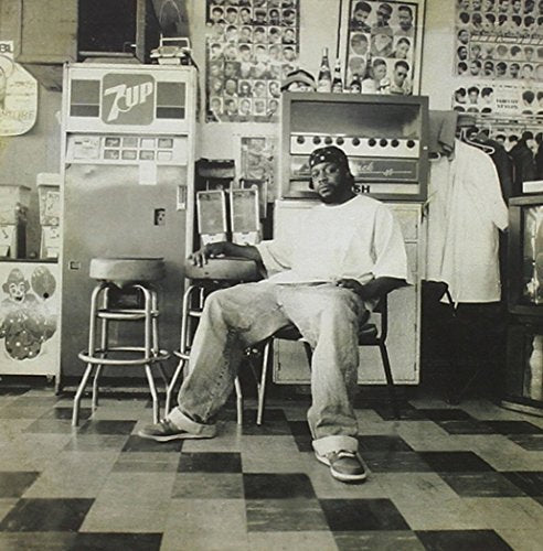 Black and white photo of a man seated in a store, CD cover.