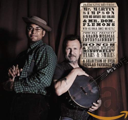 Two musicians with banjo and guitar, promotional poster in background.