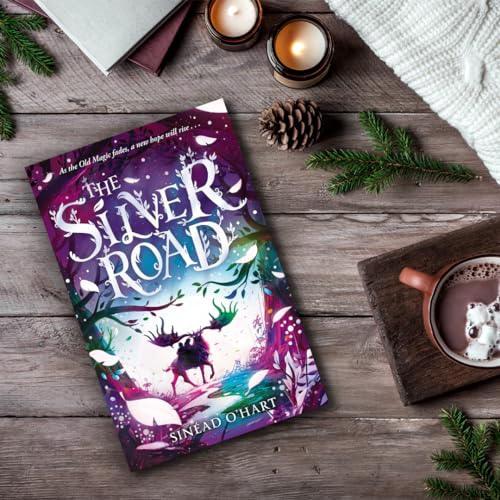 Book cover, "The Silver Road," with candles, pine branches, and a mug.