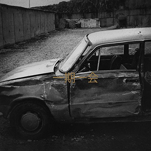 Black and white photo of a damaged car with Japanese text overlay.