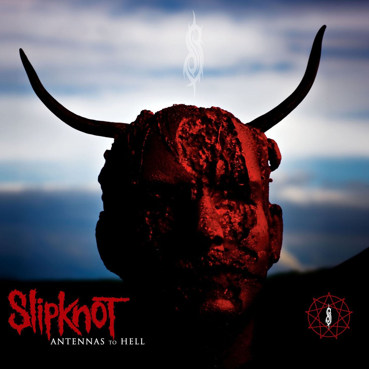 Red, horned head against a stormy blue sky; Slipknot album cover.