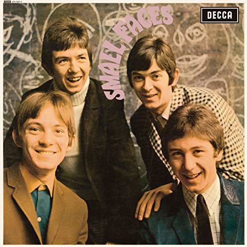 Four young men in suits and collared shirts smiling at the camera together.