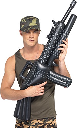 Man in camouflage clothing holding a large black inflatable machine gun against a white background.