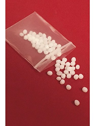"White, round beads spilling from a clear plastic bag onto a red background."