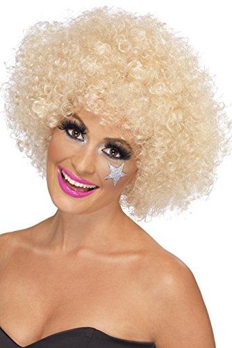 A woman wearing a blonde afro wig and glamorous makeup, smiling directly at the camera.
