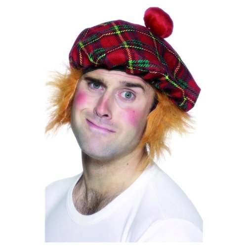 Man wearing a red tartan hat with a pom-pom and fake red hair.