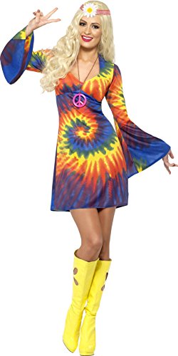 Woman wearing a tie-dye dress, yellow boots, and a headband, making a peace sign.