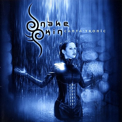 Woman in black latex stands in a blue, watery, stone environment.