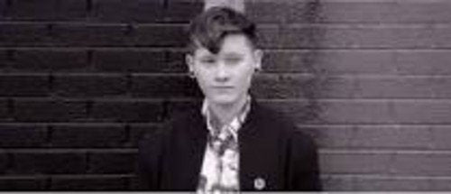 Black and white portrait of a person with styled hair and a blazer.