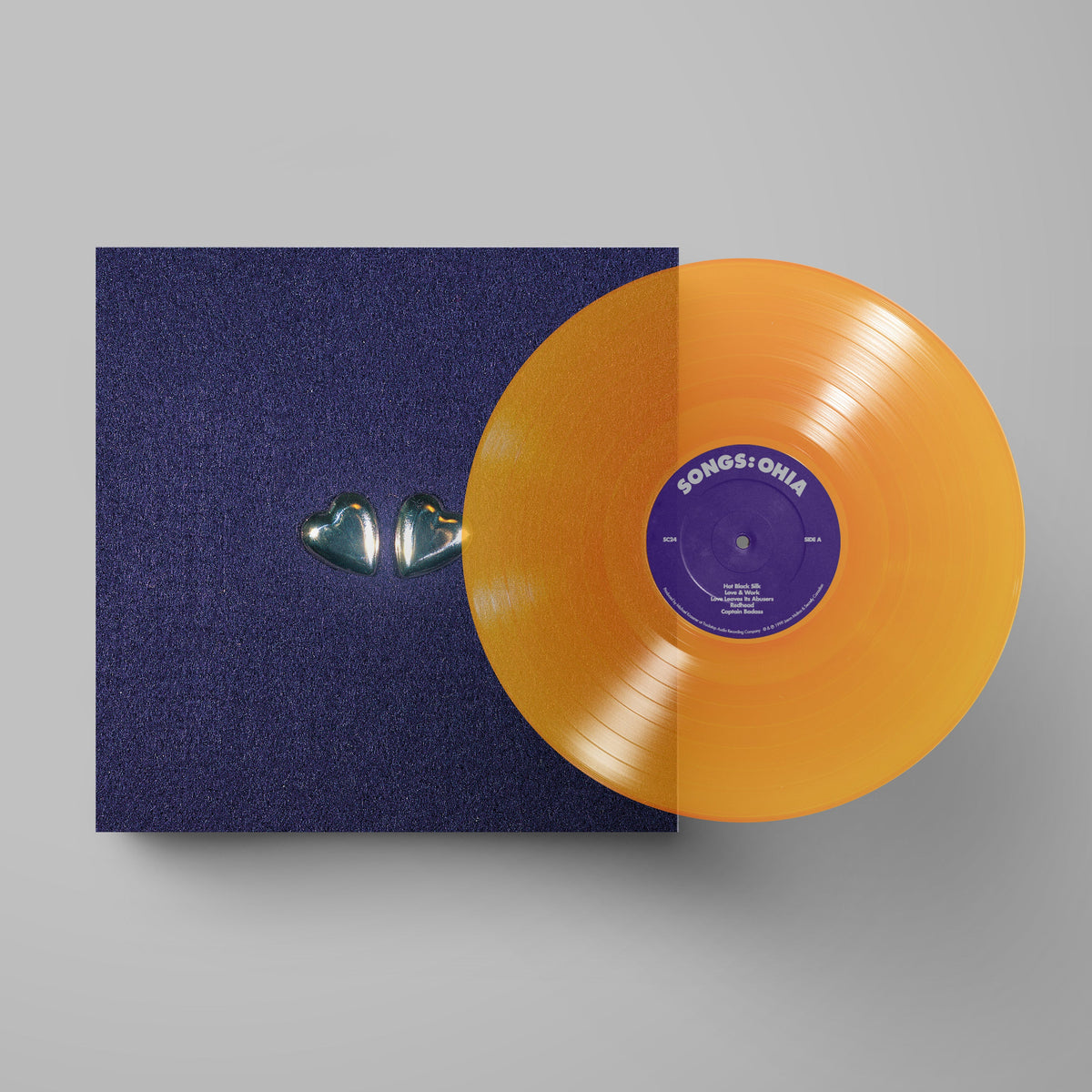 Clear orange vinyl record with blue album cover featuring a heart shape.