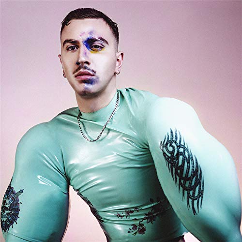 Man with painted face and floral tattoos wearing a light green suit.