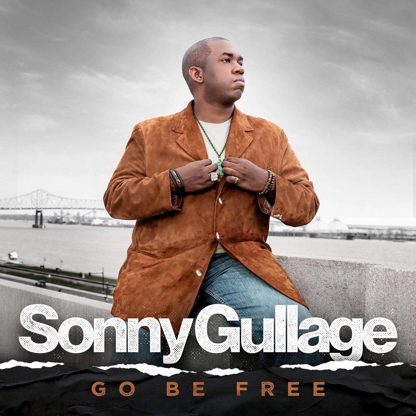 A man in a brown jacket sits against a bridge background, album cover art.