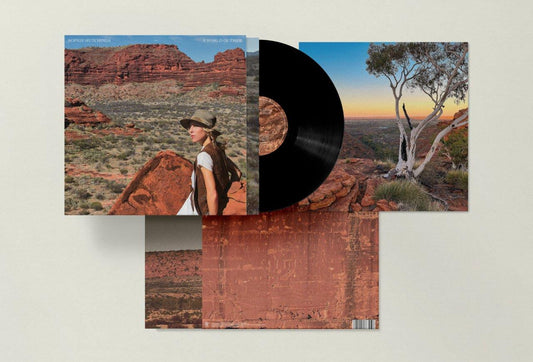 The image shows a vinyl record and its packaging, featuring desert landscape photographs.