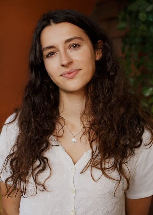 Young woman with long, wavy brown hair and a slight smile.