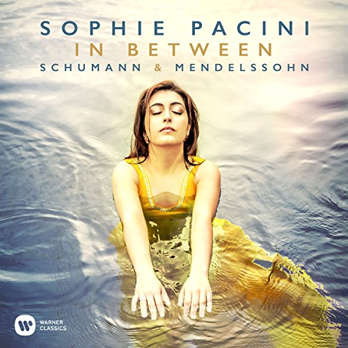 Sophie Pacini in yellow dress, eyes closed, hands together, surrounded by water.