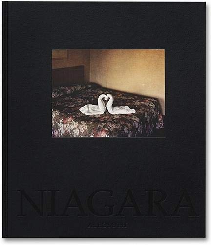 The image depicts a black book cover with a photograph of a bed. The alt text for this image is: "black book cover with 'Niagara' embossed on the bottom, featuring a photo of a bed with towels shaped like swans."