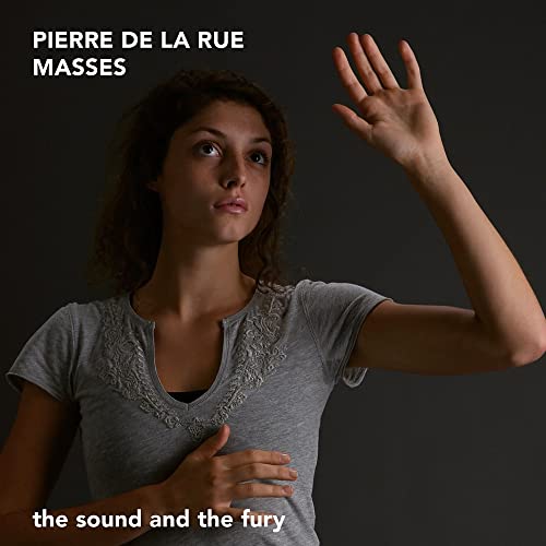 A woman in a grey shirt looks upward with one hand raised against dark background.