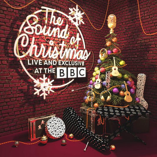 "Christmas album cover featuring a decorated tree and musical instruments against a brick wall."
