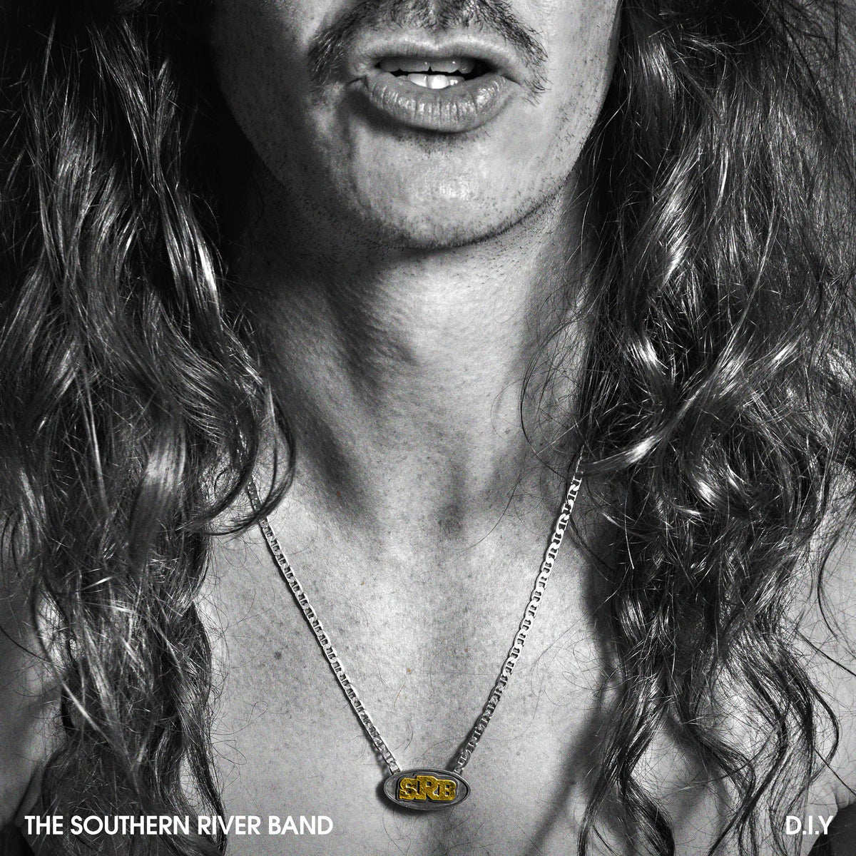Black and white close-up of a man with long hair and a necklace.