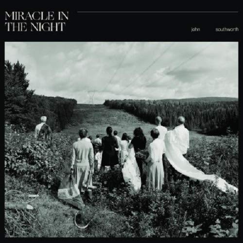 "Black and white vinyl album cover featuring a group walking in a field."