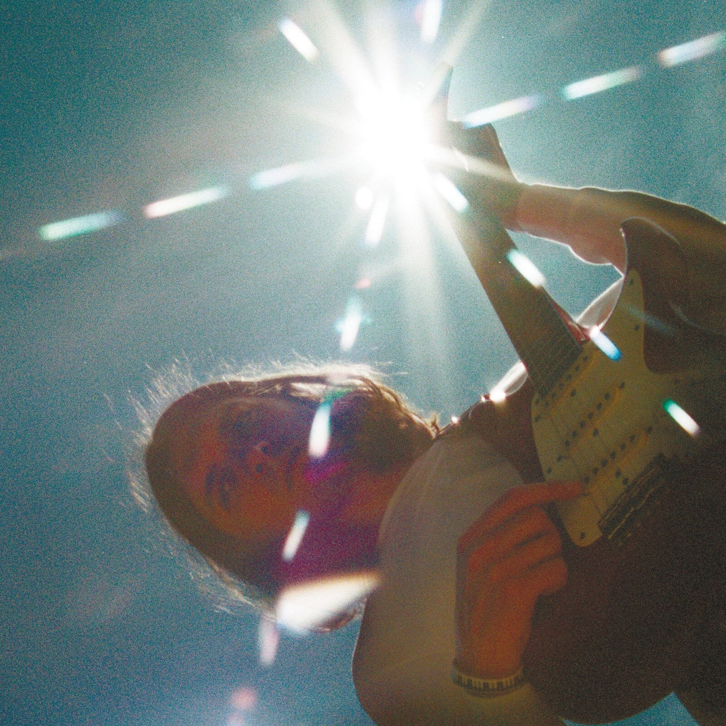 Guitarist performing on stage with bright, blurred stage lights.