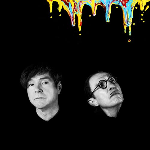 Black and white portrait of two men under colorful dripping paint.