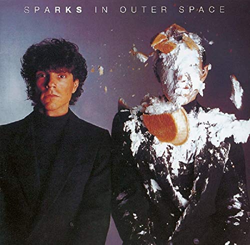 Two men in dark suits, one with a pie smashed into his face.