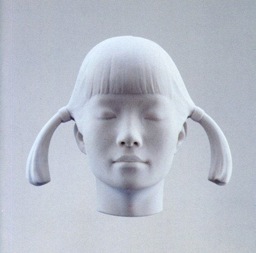 White sculpture of a young girl’s head with closed eyes and pigtails.