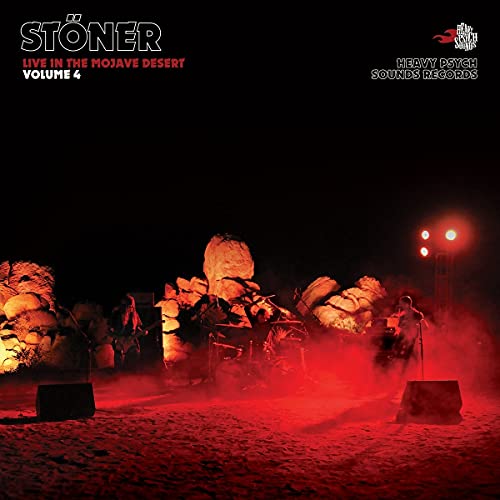 Stöner performing live in a desert landscape illuminated by red stage lights at night.