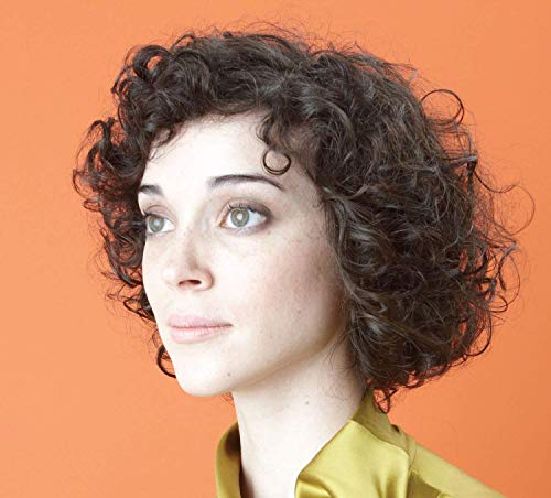 St. Vincent portrait, curly dark hair, looking off-camera, orange background.