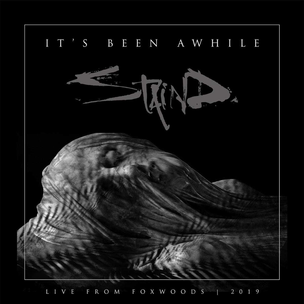 Staind album cover: hooded figure with arms outstretched, dark background.