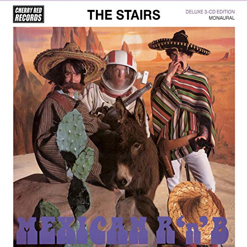 Three men in costumes, including a space helmet and sombreros, pose with a donkey.