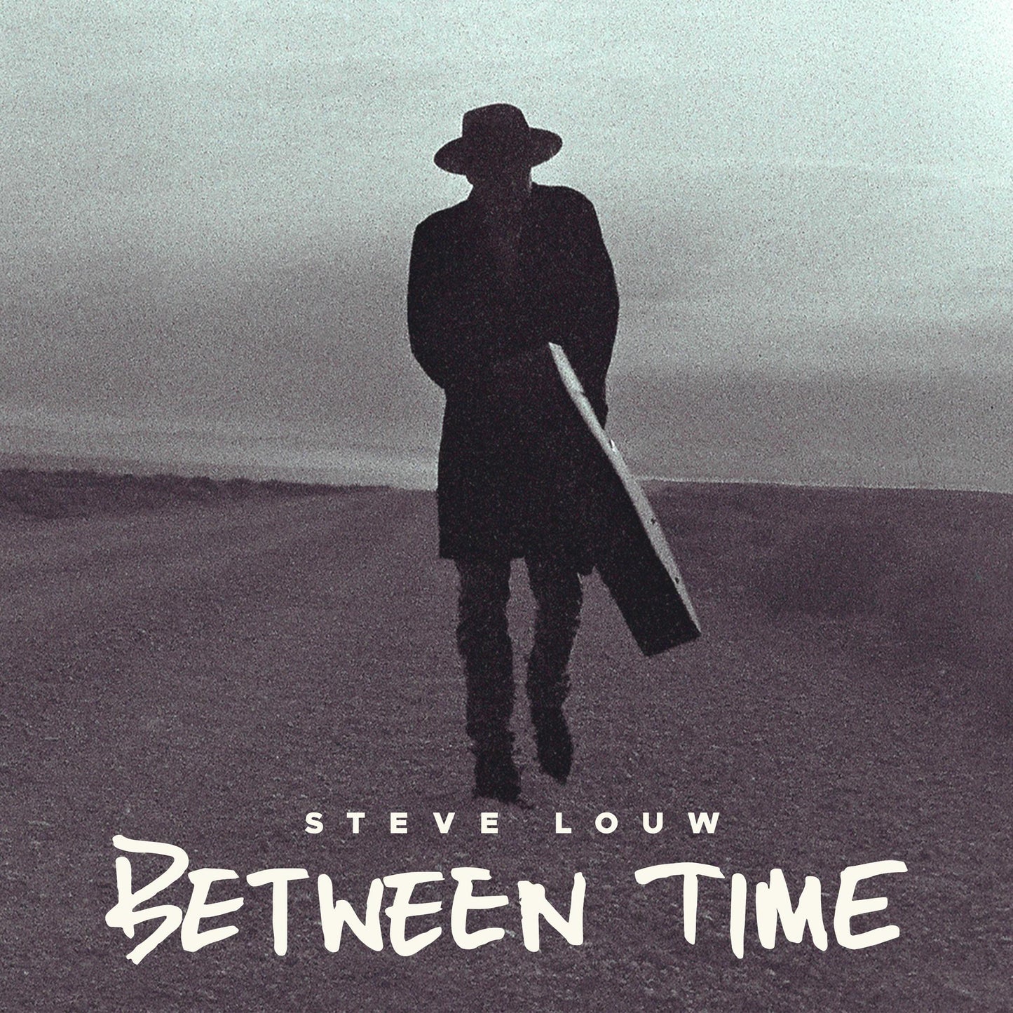 Silhouette of a man in a hat carrying a guitar case across a landscape.