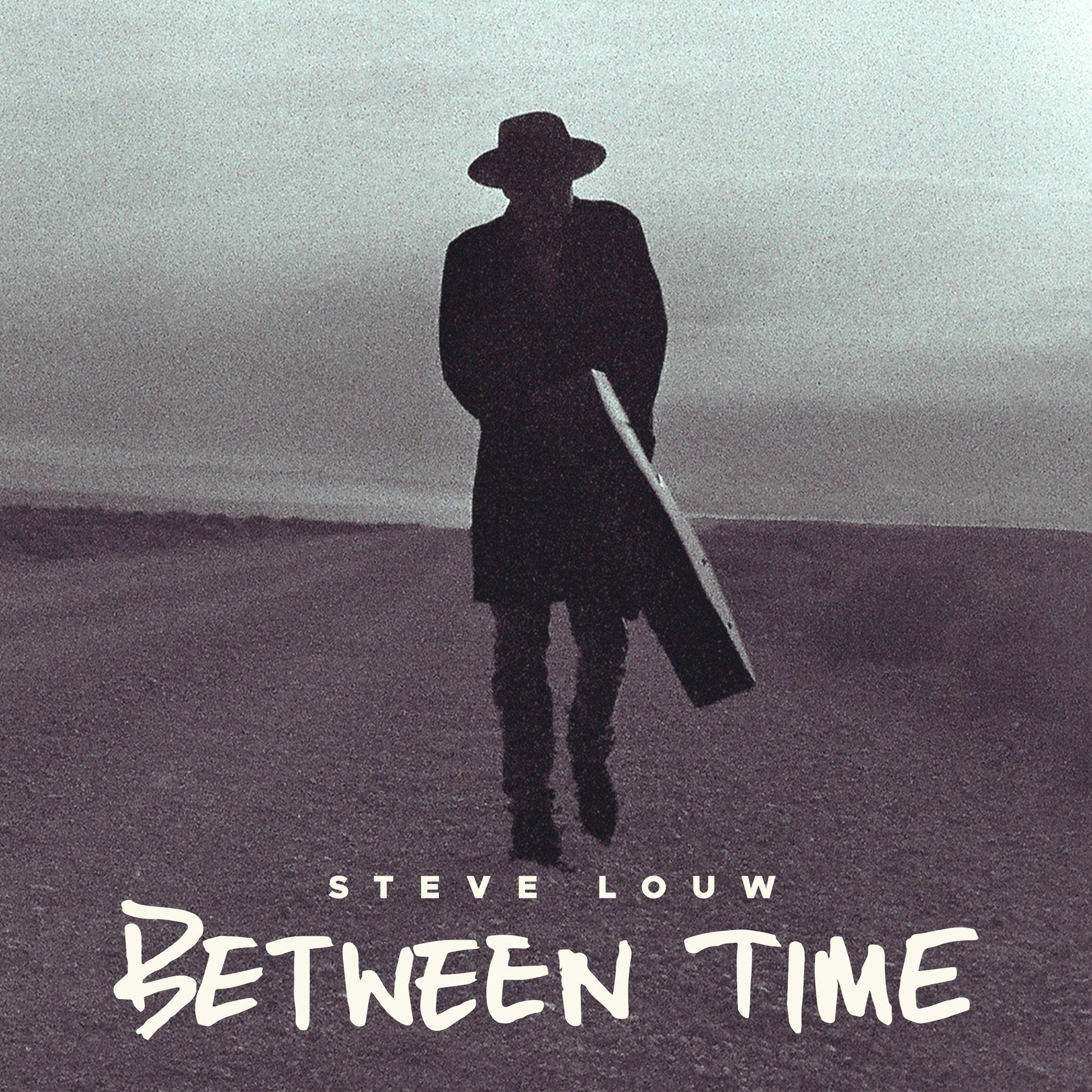 Silhouette of a man in a hat carrying a guitar case across a landscape.