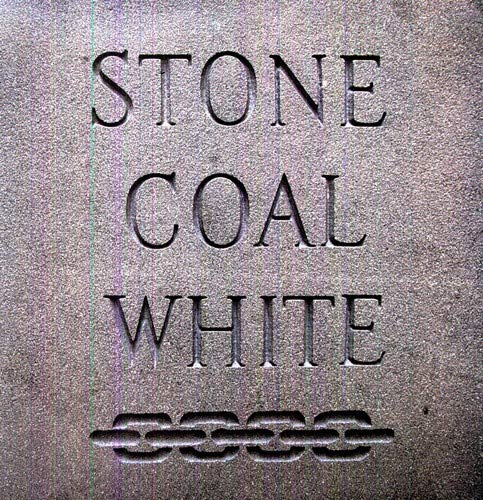The text STONE COAL WHITE is carved into a textured gray stone surface.