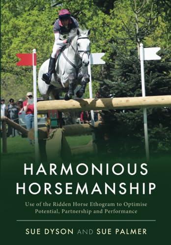 A rider on a grey horse jumping a log fence in a grassy field.