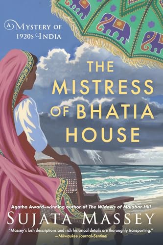 A woman in a pink sari stands by a chair overlooking a stormy sea.