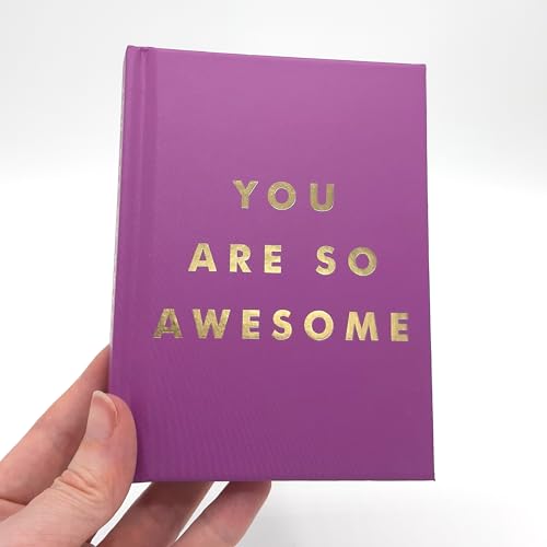 A hand holds a purple book with the gold text You Are So Awesome.