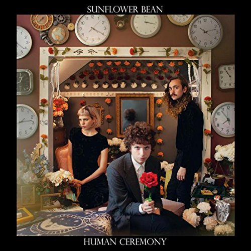 "Album cover featuring three people surrounded by clocks and flowers, with 'Sunflower Bean' and 'Human Ceremony' text."