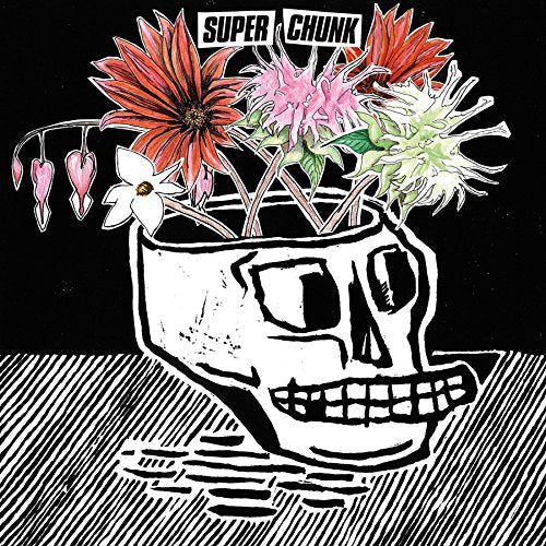 A skull-shaped vase filled with colorful flowers against a black and white background.