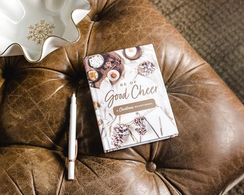 A Christmas devotional book and white pen on a brown leather tufted ottoman.