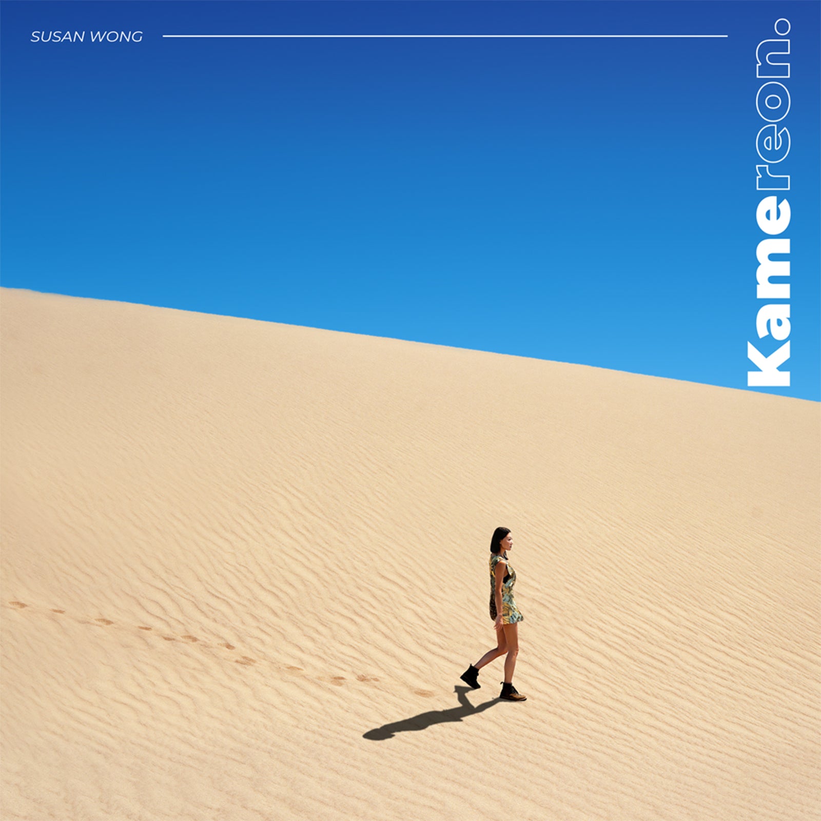 CD cover: woman walking on sand dunes under a blue sky.