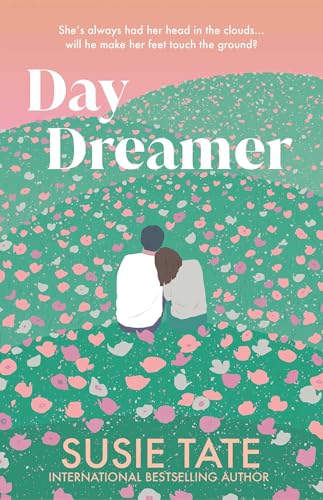 A couple sits together in a green field filled with scattered pink and white flowers.