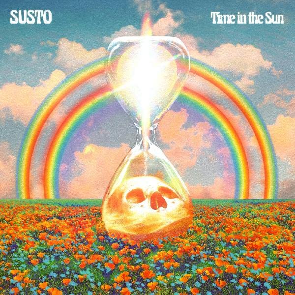 An hourglass containing a skull sits in a flower field under a rainbow sky.