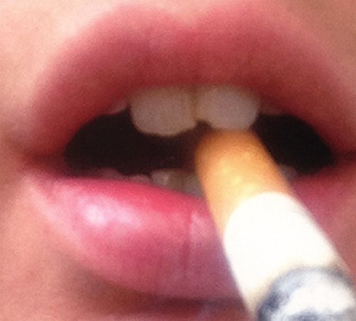 Close-up of lips holding a lit cigarette, dark and moody aesthetic.
