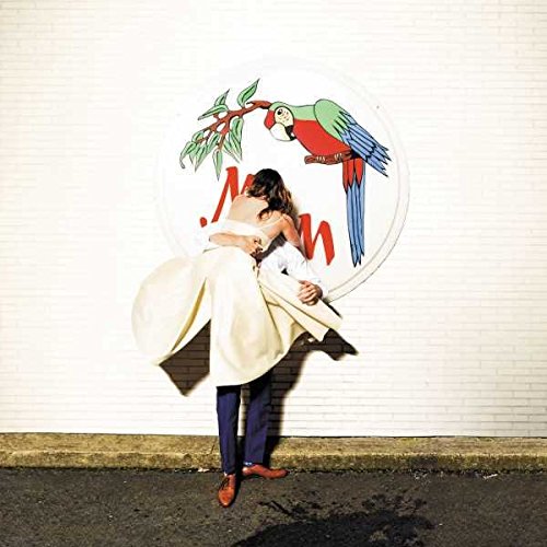 Couple embracing in front of a large circular parrot image.