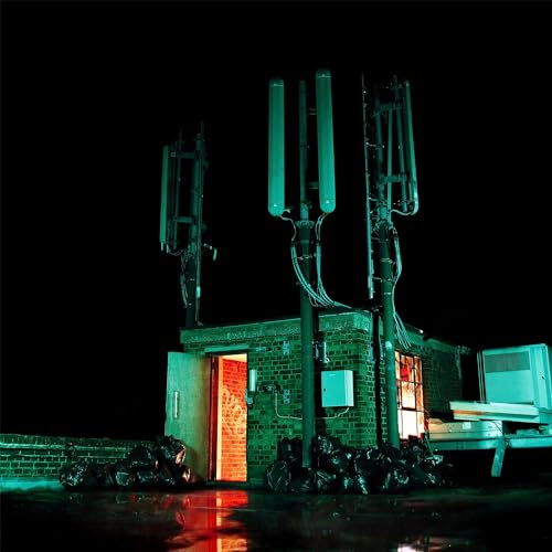 A brick structure with cell towers at night, illuminated by green and orange light.